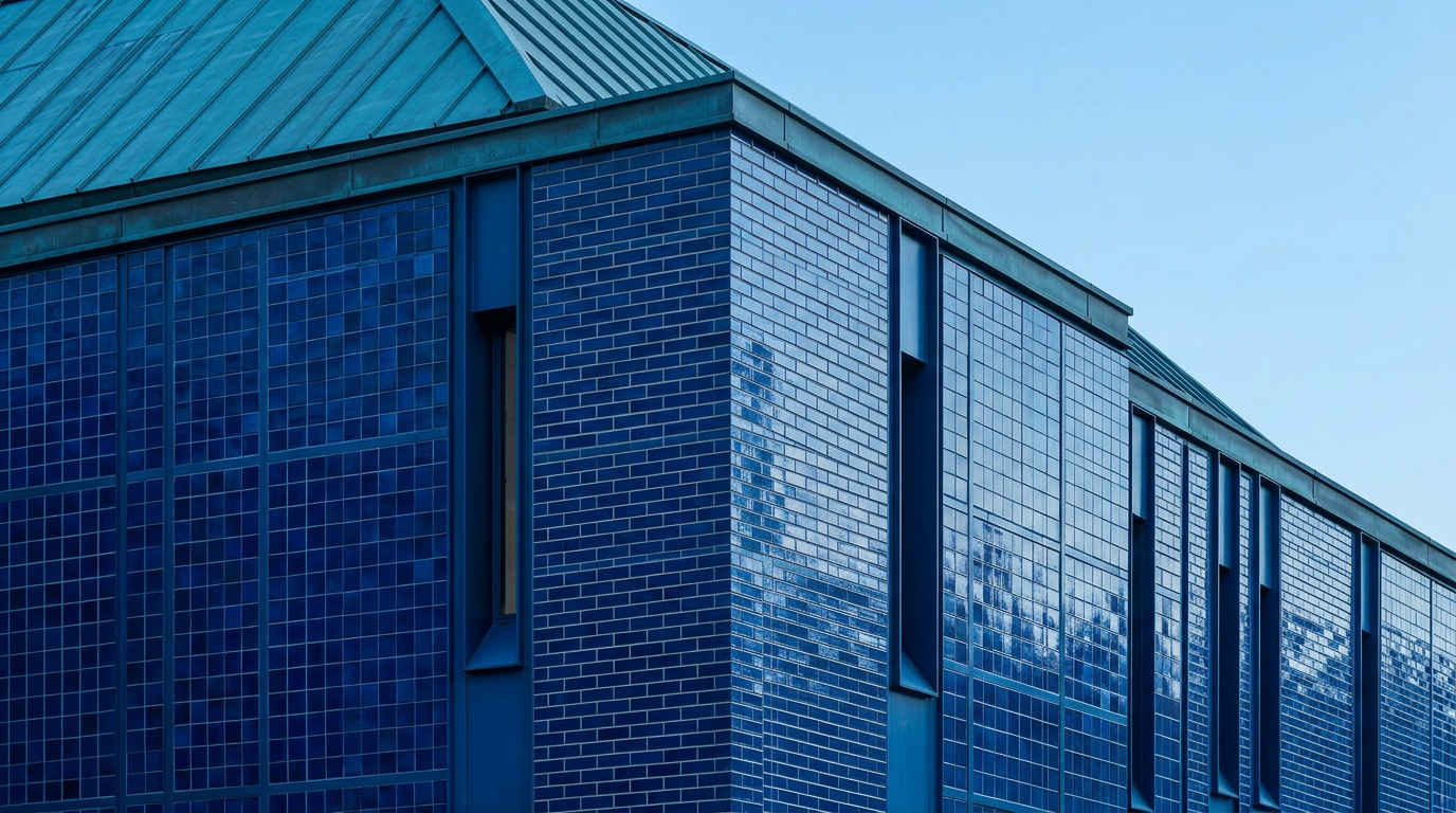 Blue tiled brick and grid panels cover a building with a blue metal roof, viewed from a low angle against a clear sky.
